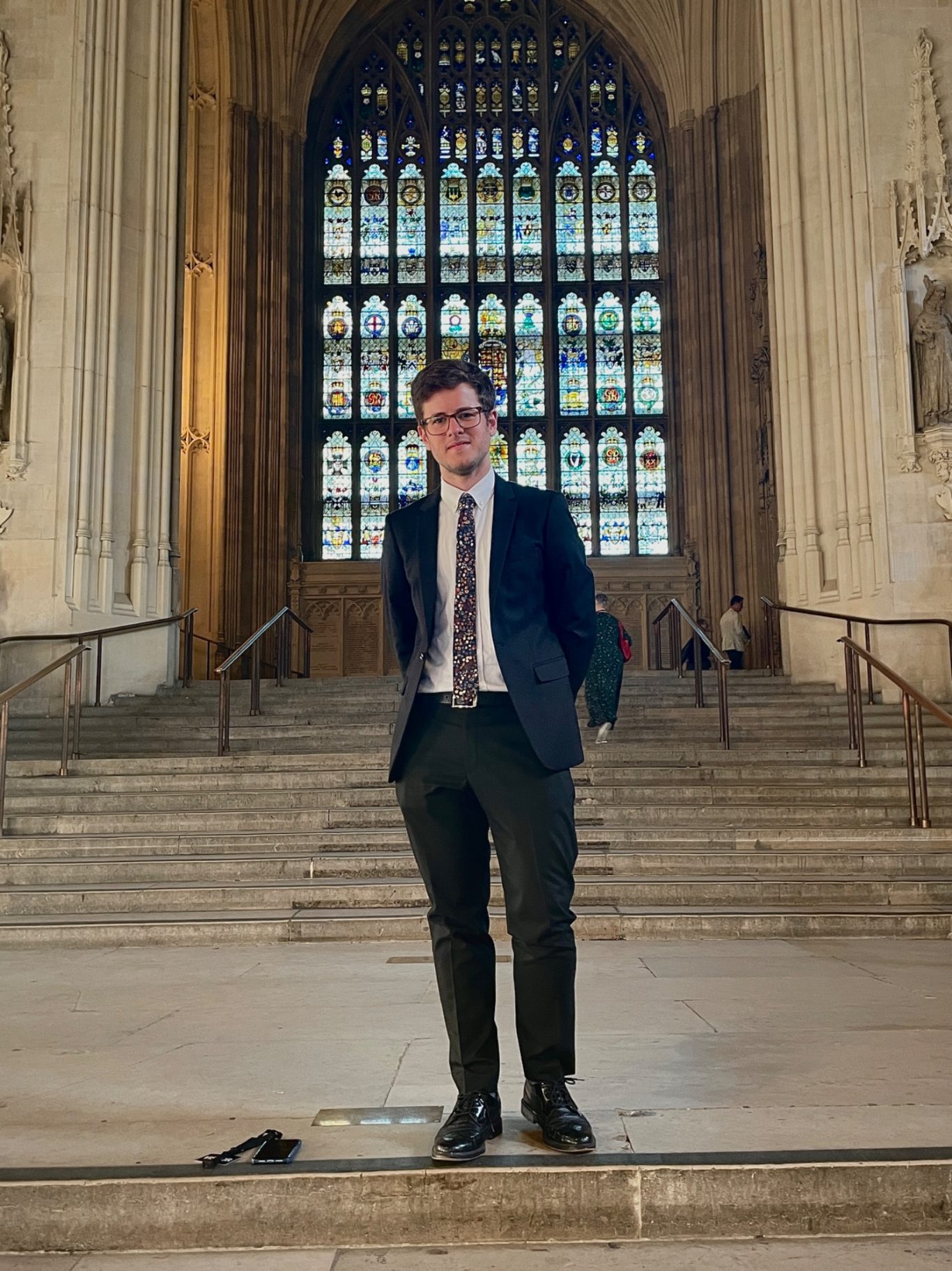 With a background in politics, JK can help reach political stakeholders. JK stands on the iconic stairs inside Westminster Hall in the Palace of Westminster wearing a suit.